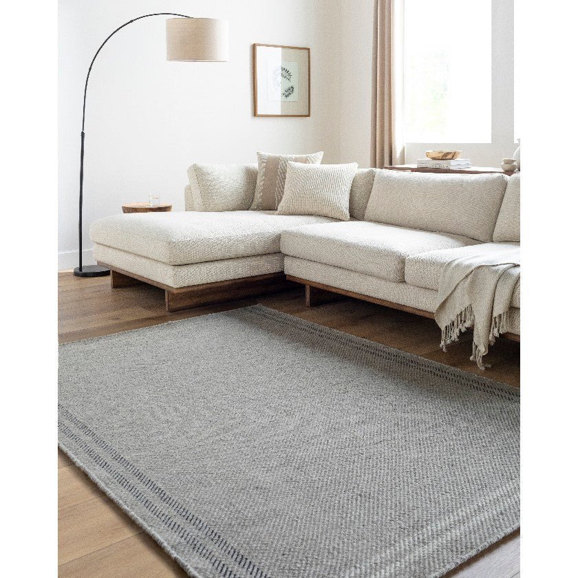AAAB8702-576-roomscene_201-1 Janmichael Solid and Border Gray/Black Area Rug - Image 1