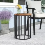 Goldoma 15 inch round solid wood outdoor side table with black metal frame on a patio
