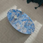 Goldoma oval blue fiberglass coffee table with marble-like finish in a modern living room