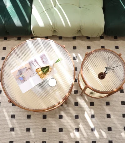 Modern farmhouse nesting coffee table set with ribbed glass tops and copper accents on a living room floor
