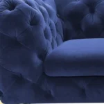 Blue velvet loveseat with gold legs and diamond tufting in a living room