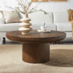 Modern round coffee table with wood veneer top and cylindrical legs in a living room setting