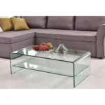 Goldoma 43-inch glass sled coffee table with brass frame and lower shelf in a modern living room