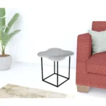 Goldoma 15 inch free form modern white marble end table with black metal base placed beside a sofa in a living room