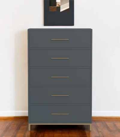 Gray solid wood dresser with five drawers and gold handles in a bedroom setting