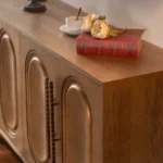 Goldoma gold sideboard buffet cabinet with solid wood arched doors and gold hardware in a modern dining room