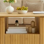 Modern oval coffee table with drawers and shelf in natural solid wood placed in living room