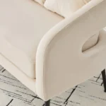 Modern velvet loveseat settee with cross back design, three decorative pillows, and metal legs in a living room setting