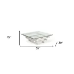 Goldoma 39-inch square glass coffee table with stainless steel sled base and lower shelf in a modern living room setting