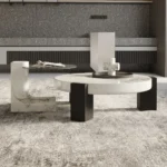 Goldoma modern round coffee table with white MDF base and clear glass top in a living room setting