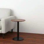 Goldoma 24 inch round end table with white veneer top and black pedestal base in a living room setting