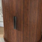 Cylinder end table with charging station in natural wood finish, featuring sliding door storage and USB ports
