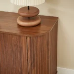 Modern TV stand with wave pattern design and adjustable shelves for TVs up to 64 inches, shown in natural wood finish