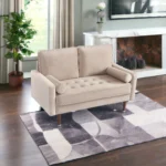 Goldoma 57-inch beige velvet loveseat with tufted seat, track arms, dark brown wood legs, and two toss pillows in a modern living room