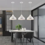 The 3-head chandelier in a minimalist hallway, casting shadows on the wall.