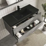 Industrial grey vanity against a brick wall, with a vessel sink and brushed nickel fixtures, angled view.
