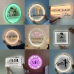 Acrylic sign with pink neon-like backlighting, mounted in a nail salon with manicure stations visible.