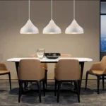 The 3-arm chandelier suspended in a restaurant setting, illuminating a rustic wooden table.