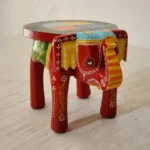 Handcrafted mango wood elephant ottoman stool with hand-painted Rajasthani folk art used as a bohemian side table in living room