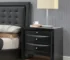 Black nightstand with drawers and pull-out tray in a modern bedroom setting