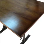 Goldoma 48 inch solid wood and iron trestle dining table with brown top and black base in a dining room setting