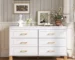 Modern white 6 drawer dresser with metal handles and solid wood legs in a bright bedroom