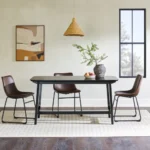 Mid-century modern dining table with black ash veneer top and trestle base in a dining room setting