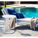 White aluminum outdoor side table with foldable legs and rounded granite finish placed on a patio