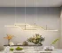 Modern 3-light LED pendant light in black, hanging above a wooden dining table in a bright room.