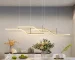Modern 3-light LED pendant light in black, hanging above a wooden dining table in a bright room.
