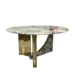 Modern round dining table with white marble top and gold stainless steel base in a bright dining room
