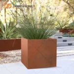 Retro style corten steel planter paired with a small shovel and soil, ready for planting in a sunny backyard.