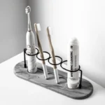 White toothbrush holder with three compartments on a marble bathroom countertop.