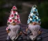 Solar garden gnome glowing in a flower bed at dusk
