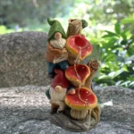 Goldoma solar light gnome in a planter, glowing against a dark background, highlighting its painted features.