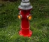 Solar garden statue fire hydrant with glowing LED and paw print detail in a flower bed