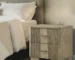 Antique oak nightstand with two drawers and grooved front panel in a bedroom setting