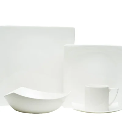 Elegant dinnerware set on white table with gold rimmed plates and bowls