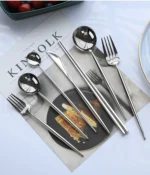 Elegant stainless steel flatware set with forks, spoons, and knives arranged on a wooden table