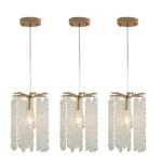 Set of three mini crystal chandeliers in gold, suspended at varying heights over a dining table.