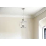 Close-up of the silver metal tapered shade of the HMS hanging light, highlighting the textured finish and warm glow.