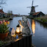 White solar rabbit statue placed among colorful flowers in a garden bed, illuminated at dusk.