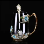 Elegant crystal glass tea mug with enamel floral design and handgrip on a wooden table