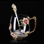 Elegant crystal glass tea mug with enamel floral design and handgrip on a wooden table
