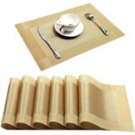 Gold weave placemats on a dining table with plates and cutlery