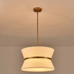 Modern chandelier with white fabric shade and brass finish hanging over kitchen island