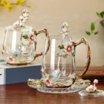 Elegant crystal glass tea mug with enamel floral design and handgrip on a wooden table