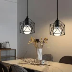 Three-quarter view of the black metal cage pendant light against a brick wall, highlighting its rustic texture.