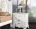 White nightstand with drawers featuring floral motifs in a classic bedroom setting