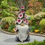 Solar gnome on stone pathway, glowing in twilight with colorful garden background.